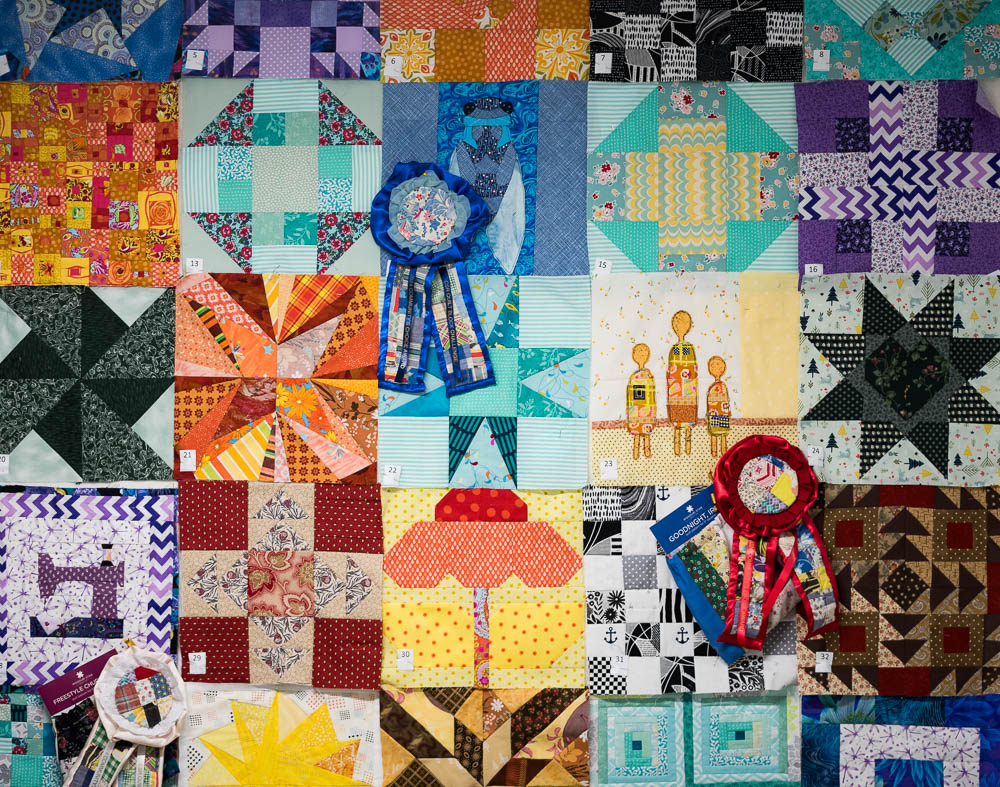 Image of a colorful quilt with a blue ribbon laying on top.